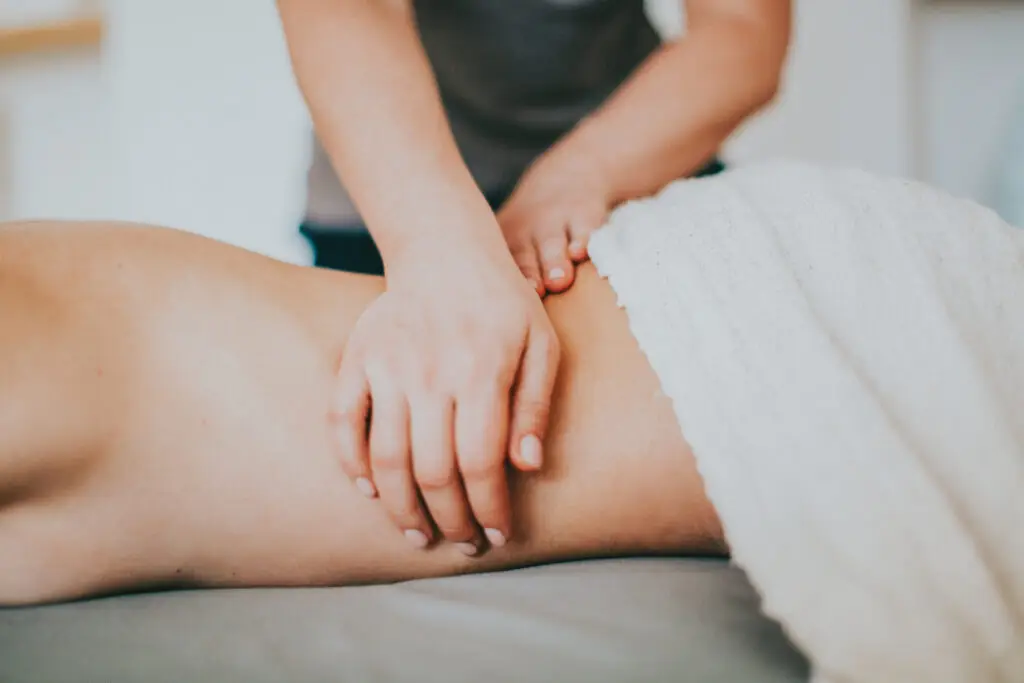 Hands massaging a person's back under a white towel