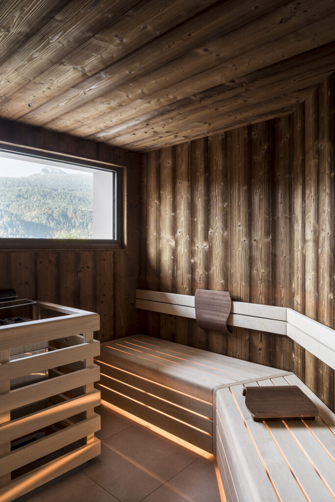 Warm wood bio-sauna interior with benches and a view through a window.