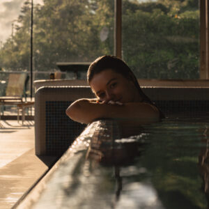 Person relaxing in a pool indoors with sunset view