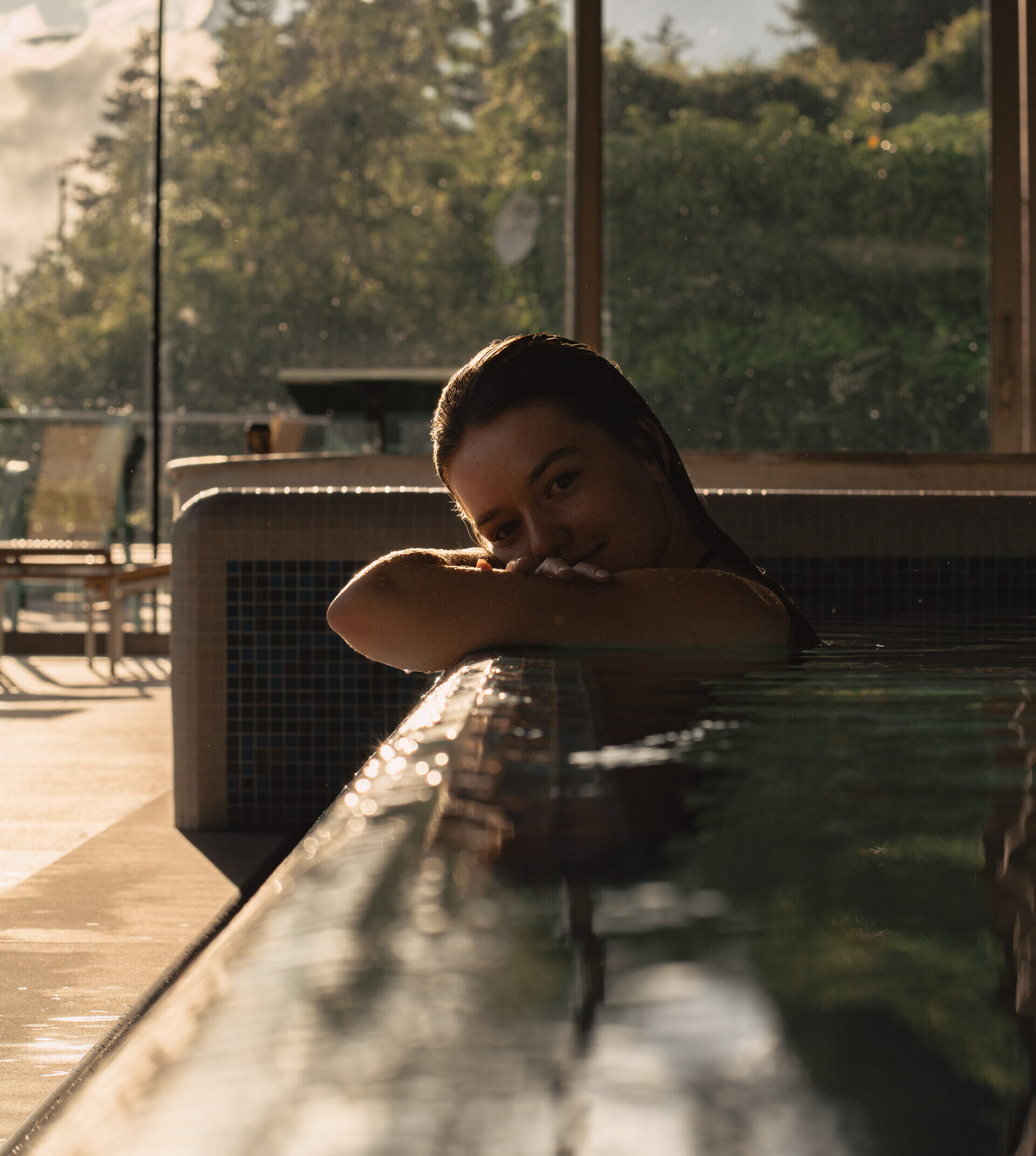 Person relaxing in a pool indoors with sunset view