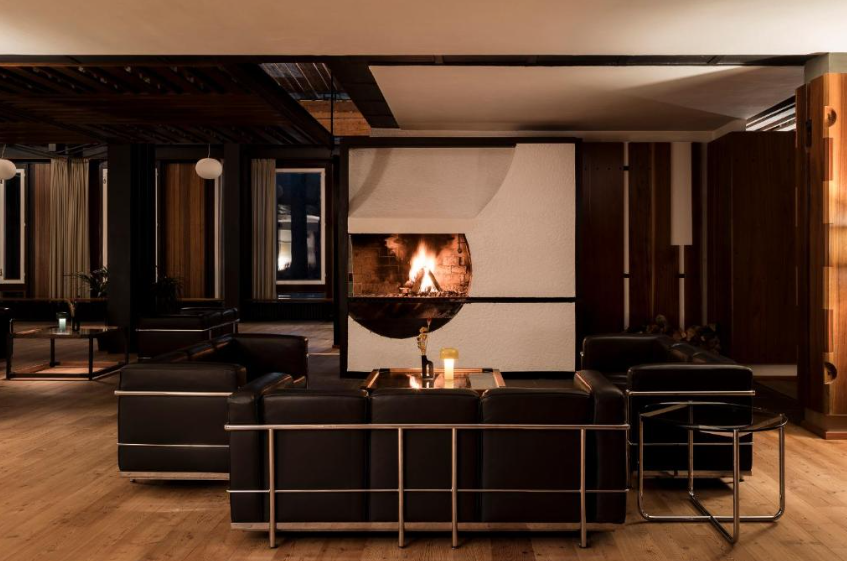 Day SPA & Night - Infra: Modern lounge with black leather couches, fireplace, and wood paneling, perfect for luxury relaxation.