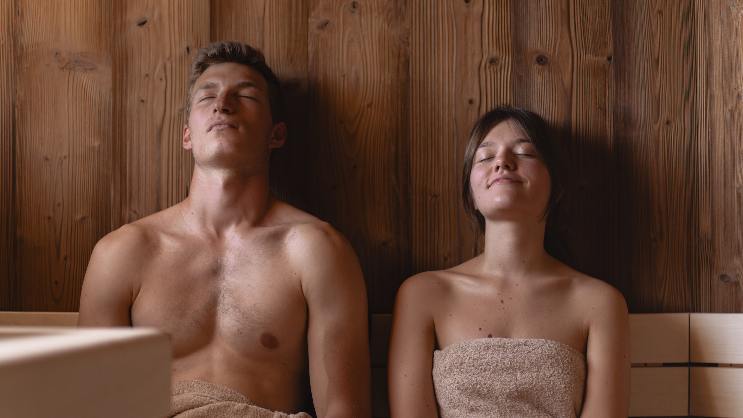 Couple relaxing in a sauna, eyes closed, enjoying a wellness ritual.